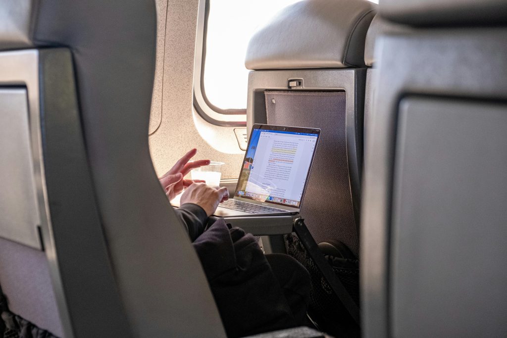 Passenger working on a laptop during flight, highlighting travel productivity.